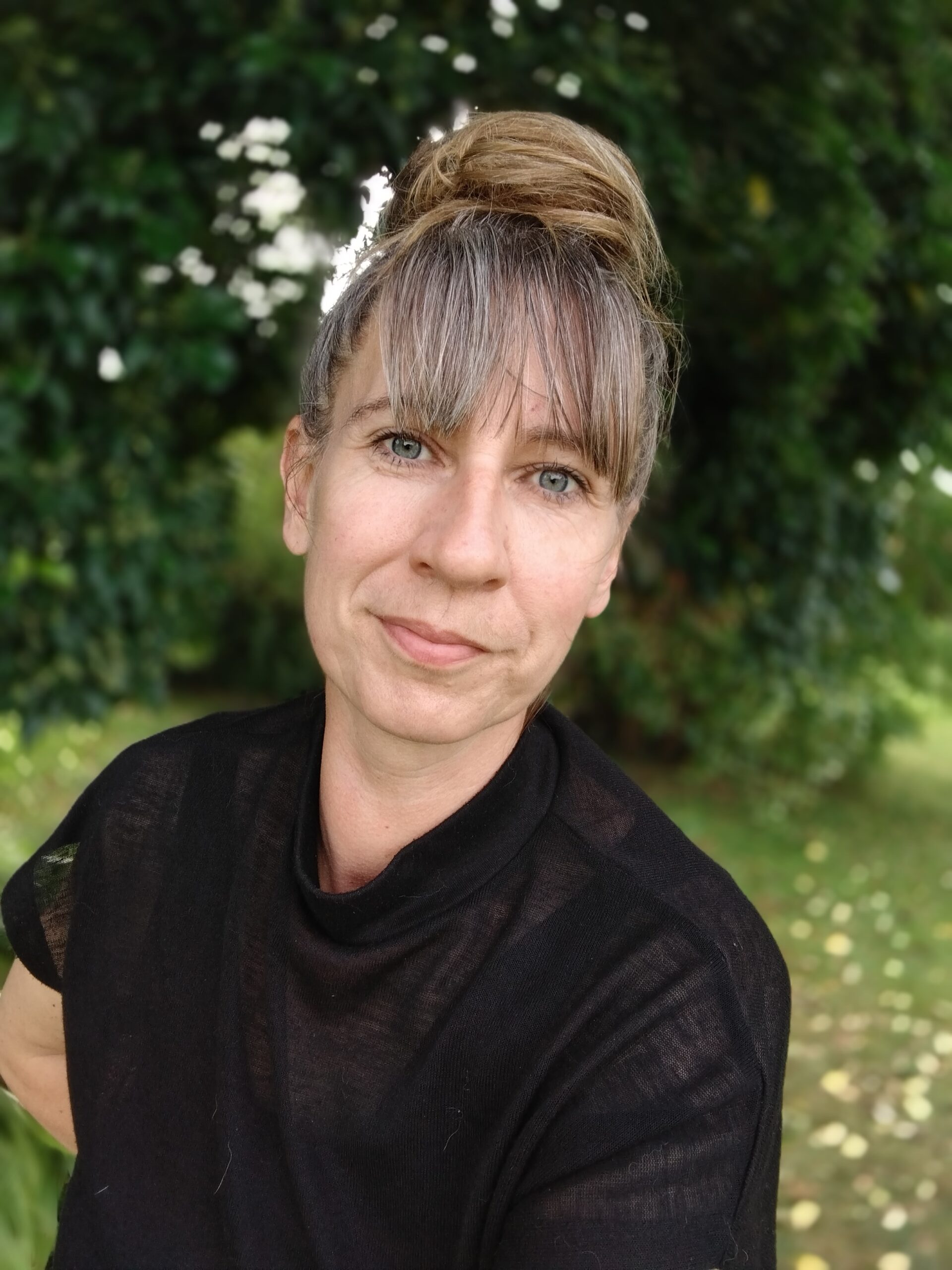 Portrætbillede af Susan, hundetræner hos Klub Hund, taget udendørs foran grønne træer.
