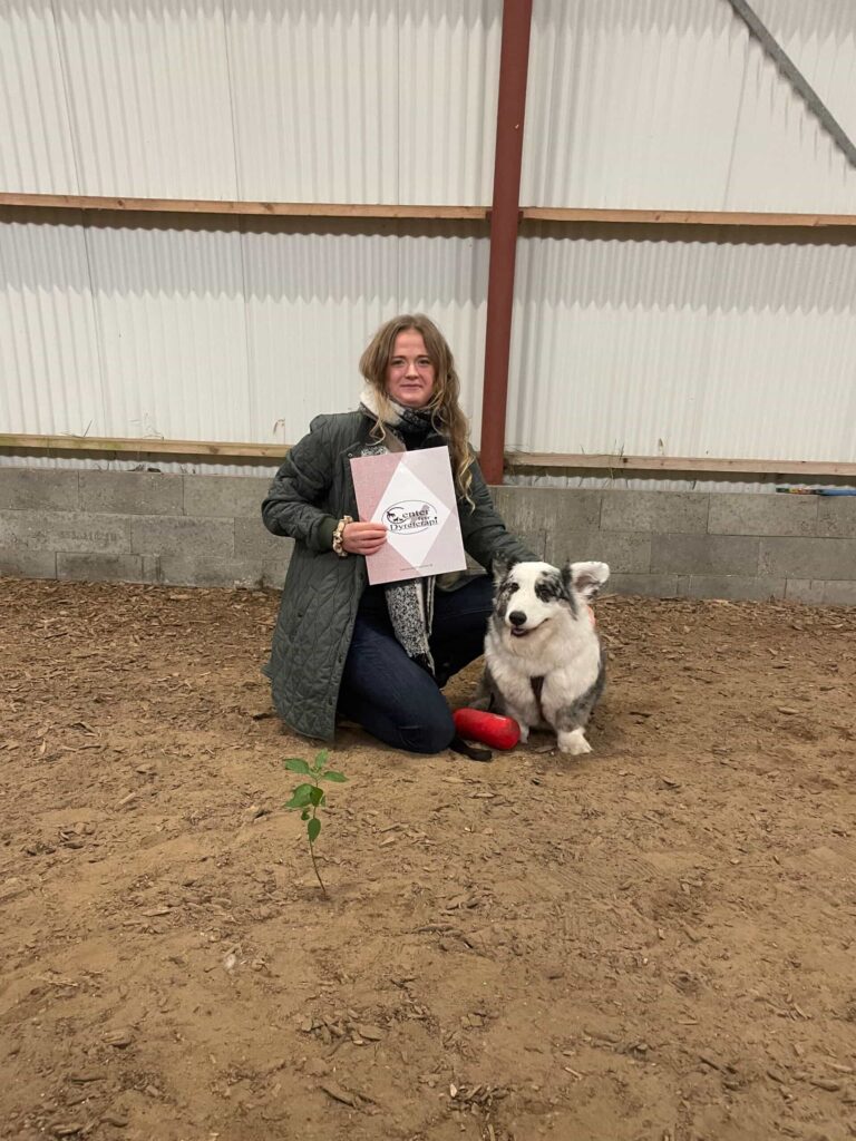 Hundetræner og backoffice-medarbejder Signe fra Klub Hund poserer stolt med sin hund og et diplom efter et kursus. Billedet viser både hendes faglige engagement og kærlighed til hundetræning, som hun bringer med ind i arbejdet hos Klub Hund.